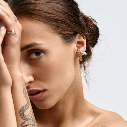 Model wearing Rawan Kanan 'The Meridian' two-tone ear crawlers featuring a polished silver wave and a textured 14K gold-plated bar.