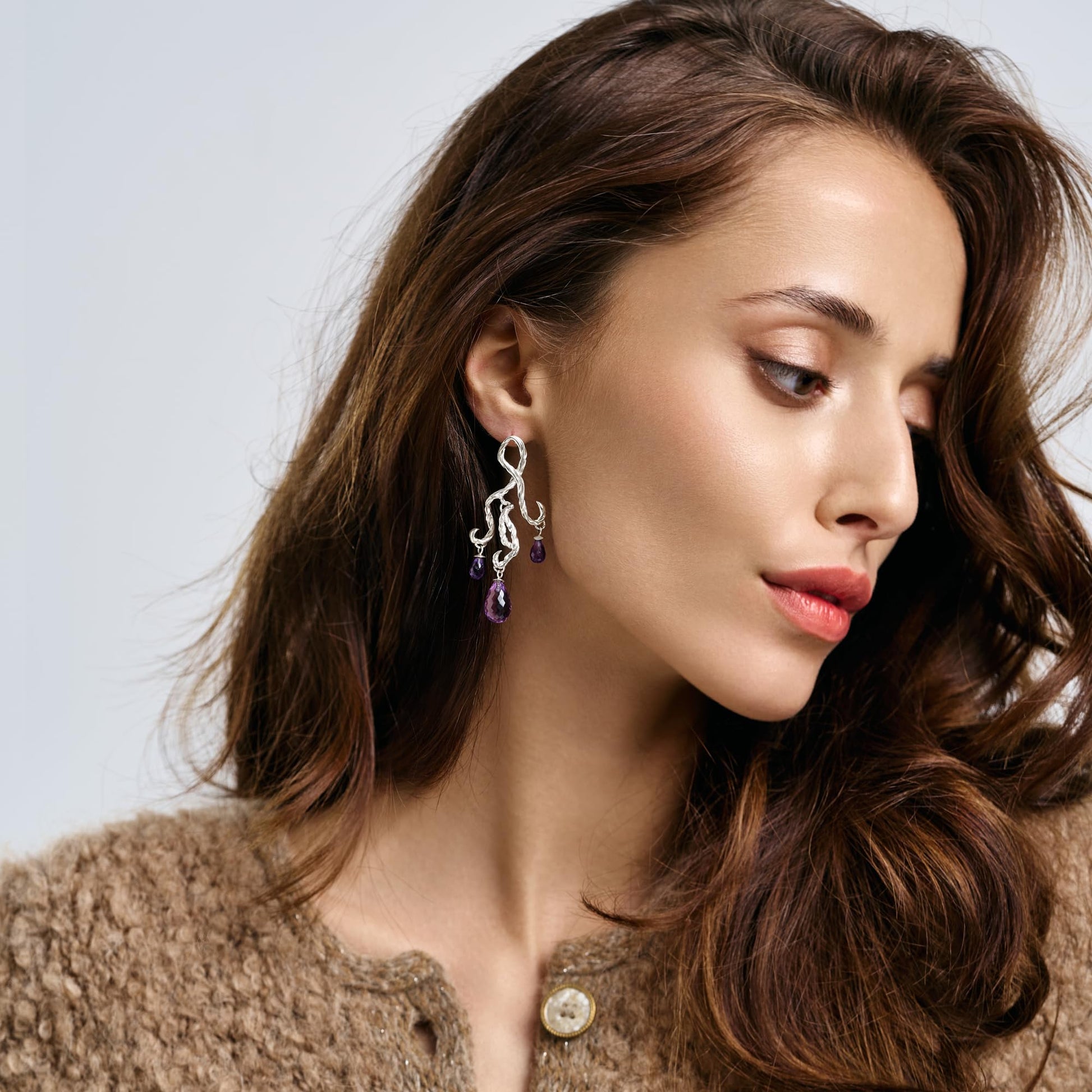 Model wearing Rawan Kanan handcrafted sculptural chandelier earrings in 925 silver with purple amethyst gemstone drops.