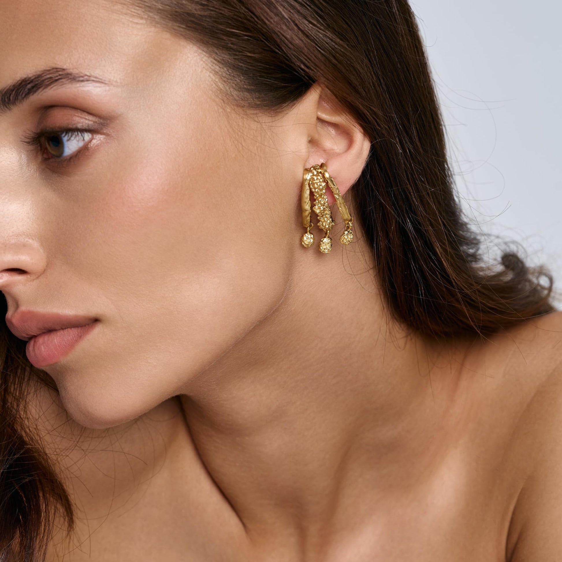 Model wearing Rawan Kanan handcrafted triple branch statement earrings in 14K gold plated silver.