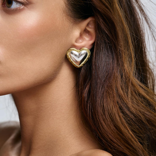 Model wearing Rawan Kanan handcrafted two-tone heart stud earrings in 925 silver and textured 14K gold frame.