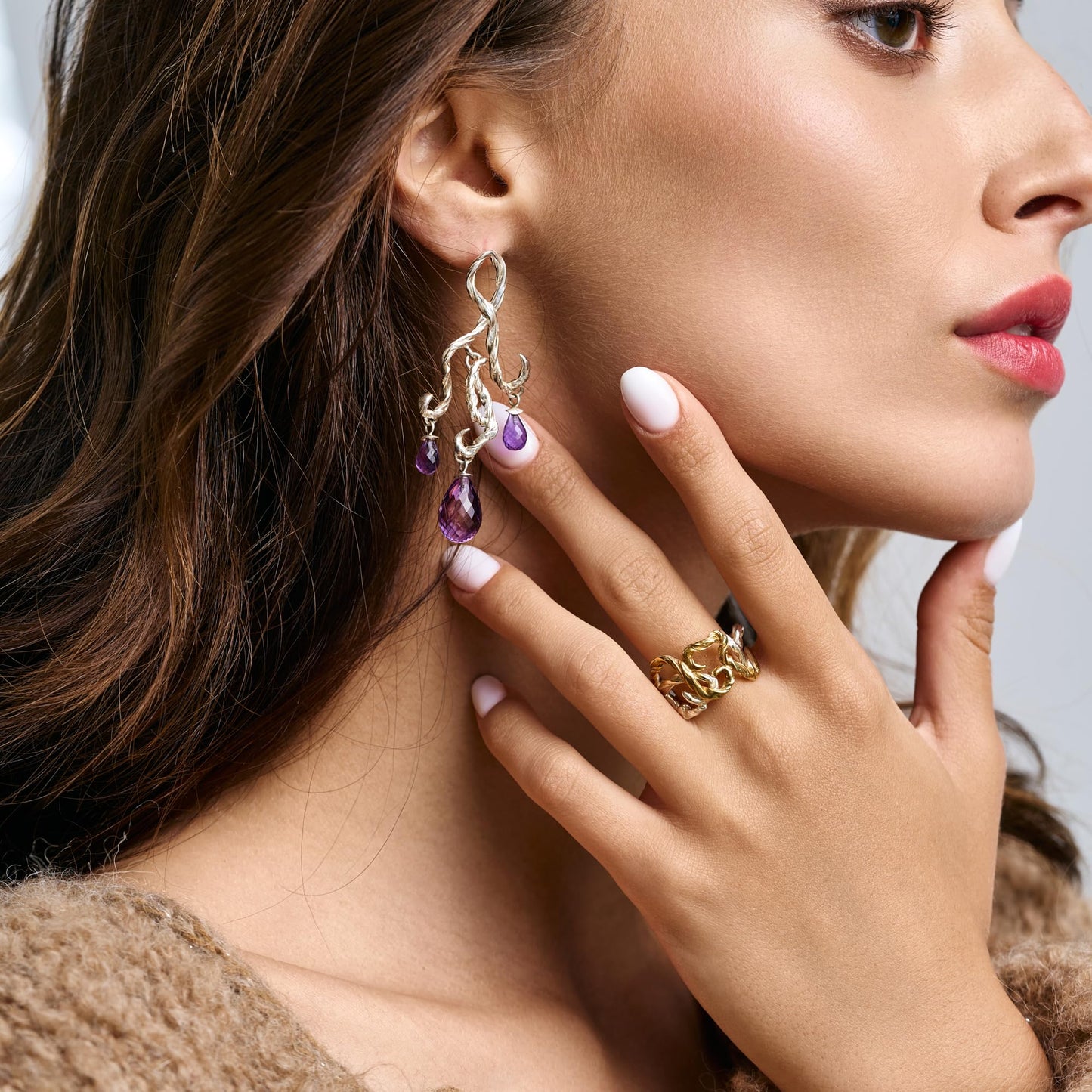 Model wearing Rawan Kanan handcrafted sculptural chandelier earrings in 925 silver with purple amethyst gemstone drops.